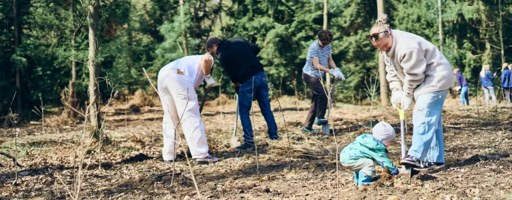 BIL-Team pflanzt gemeinsam mit Kind Baumsetzlinge auf einer Waldfläche – Pflanzaktion mit Plant-my-Tree